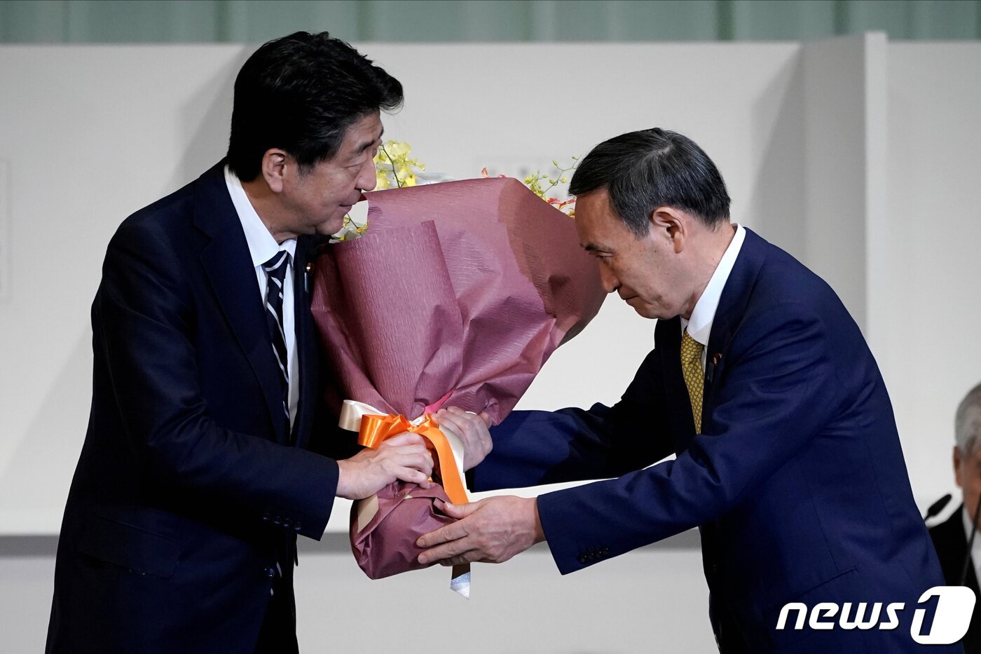 본문 이미지 - 아베 신조 일본 총리가 14일(현지시간) 도쿄의 한 호텔에서 열린 자민당 총재 선거에서 총재로 선출된 스가 요시히데 관방장관에게 꽃다발을 건네고 있다. ⓒ 로이터=뉴스1