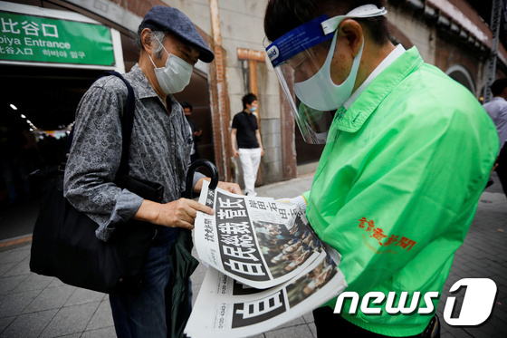 도쿄 행인들이 16일 스가 요시히데 신임 총리 선출소식을 알리는 호외를 받아보고 있다. © 로이터=뉴스1