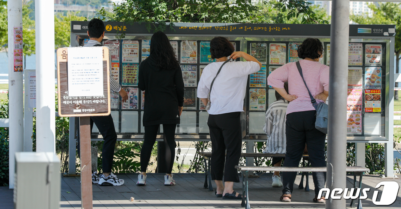 (서울=뉴스1) 안은나 기자 = 20일 오후 서울 여의도 한강공원 배달존에서 시민들이 전단지를 보고 있다. 신종 코로나바이러스 감염증(코로나19)으로 오프라인 매장의 매출이 감소하 …