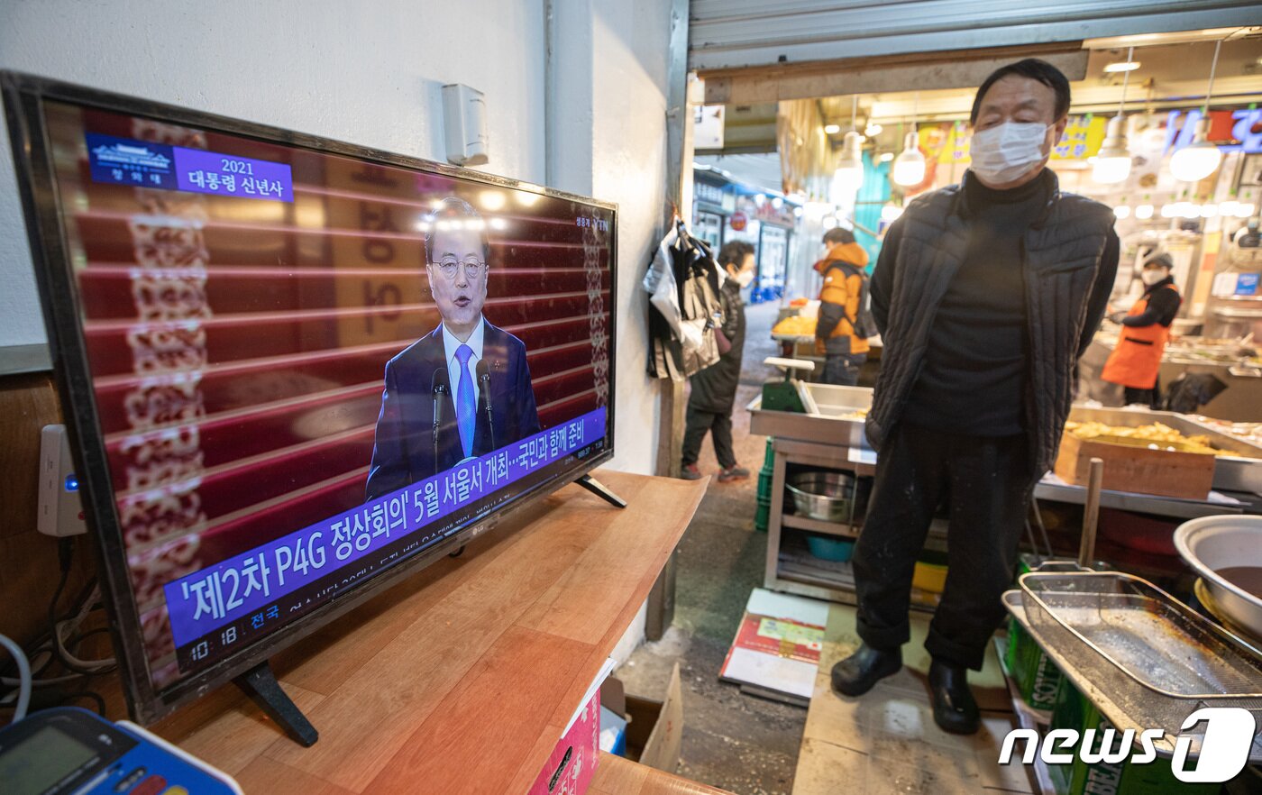 본문 이미지 - 11일 오전 경기도 수원시 팔달구 못골시장에서 한 상인이 문재인 대통령의 2021년 신년사를 바라보고 있다. 2021.1.11/뉴스1 ⓒ News1 이재명 기자