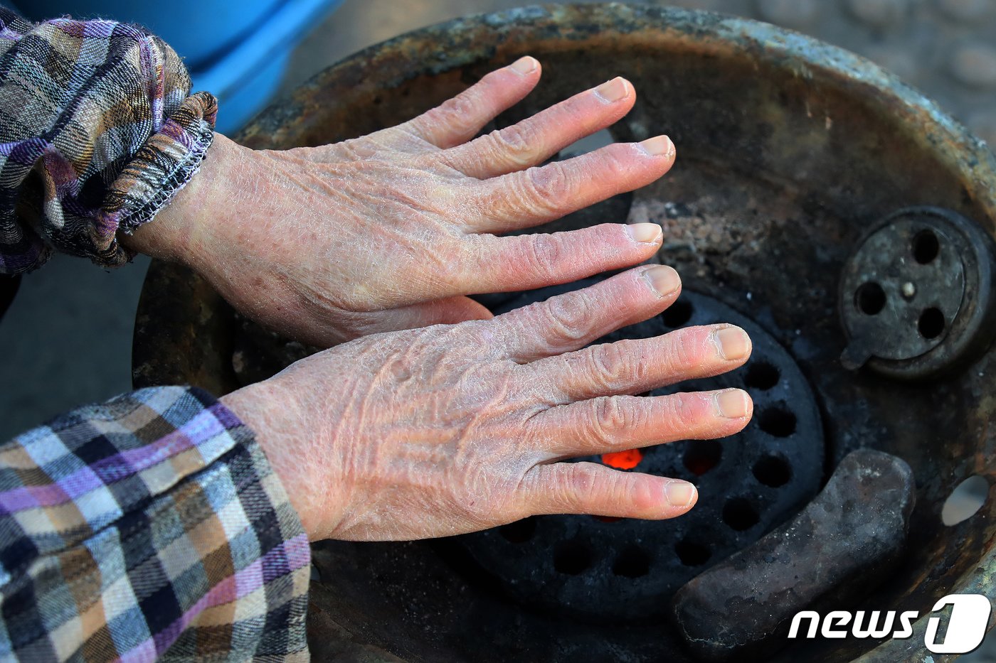 대구 북구 칠성시장에서 난전 상인이 생선을 손질하느라 꽁꽁 언 손을 연탄불에 녹이고 있다. 2021.1.19/뉴스1 ⓒ News1 공정식 기자