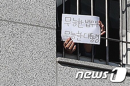 본문 이미지 -  서울 송파구 동부구치소에서 한 재소자가 '무능한 법무부, 무능한 대통령'이라는 문구가 적힌 종이를 창살 너머로 꺼내 보이고 있다. 2021.1.6/뉴스1 ⓒ News1 민경석 기자