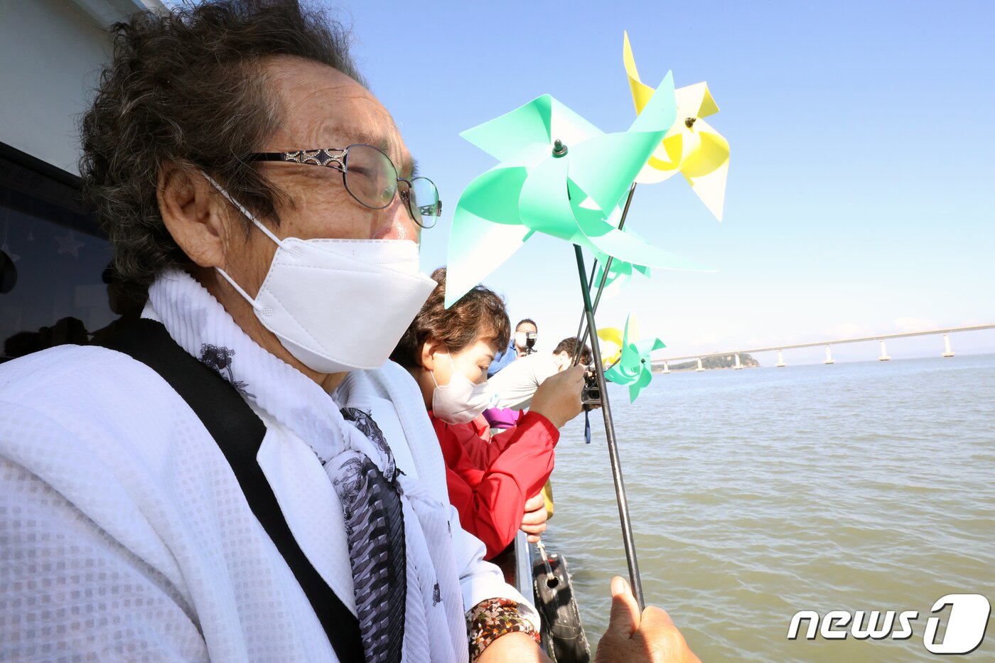 본문 이미지 - '강화 망향(望鄕)배'시범운항 행사가 열린 14일 실향민들이 한강하구 교동대교 인근에서 북녘땅을 바라보고 있다. 이번 행사는 14~15일 이틀간 열리며 실향민과 이산가족 50여명이 참석했다. 한강하구는 파주시 탄현면 만우리부터 시작해 강화군 교동도 말도섬, 개성시 판문군 임한리에서 황해남도 해남리까지의 길이 70km·면적280㎢에 이르는 곳이다. 세종실록지리지에는 조강(祖江, 할아버지강)이라 불리며 서해에서 마포나루를 거쳐 세곡선과 각종 물품을 실어 나르던 물길로 이용됐다. 한국 전쟁 후 체결된 정전협정에 따라 민간선박만 통행이 가능한 중립지역으로 지정됐으나, 출입이 통제돼 남북 간의 비무장지대와 같은 갈등의 공간으로 존재하고 있다. 2021.10.14/뉴스1 ⓒ News1 정진욱 기자