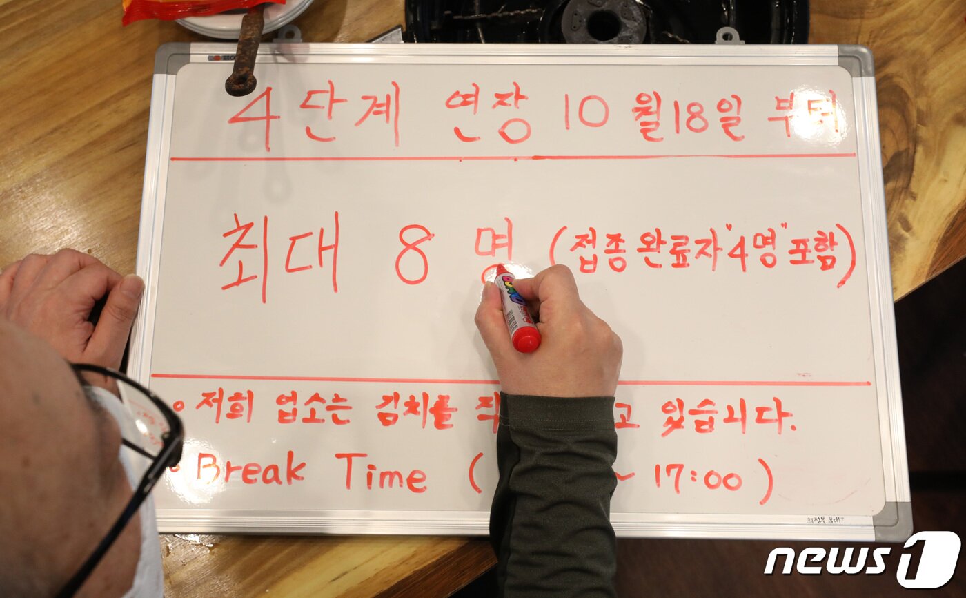 본문 이미지 - 정부가 접종 완료자를 중심으로 사적모임 허용 인원을 크게 늘린 거리두기 조정안을 발표한 15일 오후 서울시 종로구의 한 식당에서 점주가 변경될 인원제한 안내문을 작성하고 있다. 중앙재난안전대책본부는 현재 적용되고 있는 사회적 거리두기 단계&#40;수도권 4단계 ,비수도권 3단계&#41;를 18일 0시부터 31일 24시까지 2주 연장한다고 이날 밝혔으며 수도권 등 4단계 지역은 시간과 관계없이 모든 다중이용시설에서 미접종자 4명까지, 접종 완료자를 포함해 8명까지, 3단계 지역에서는 미접종자 규모는 4명으로 기존과 동일하면서 접종 완료자를 포함할 경우 10명까지 모임 규모를 늘릴 수 있다. 조태형 기자