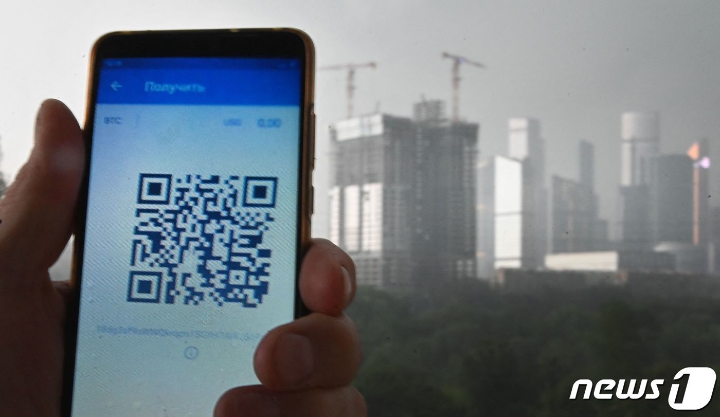 본문 이미지 - 러시아에서 큐알(QR)코드 인증제가 부활했다. 사진은 2021년 6월28일 모스크바에서 한 남성이 스마트폰의 큐알코드를 실행하는 모습. 이 큐알코드로는 △코로나19 백신 접종 여부 △최근 6개월내 감염 이력 △음성 판정 진단 내역을 인증할 수 있다. ⓒ AFP=뉴스1 ⓒ News1 최서윤 기자