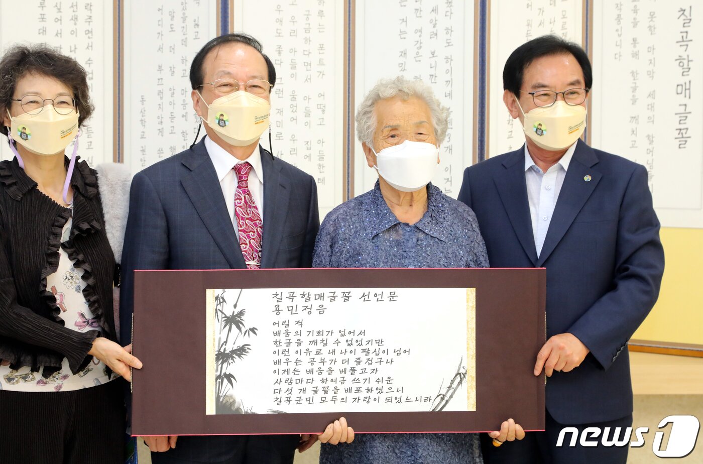 본문 이미지 - 한글날을 앞둔 6일 '칠곡할매글꼴'의 의미와 가치를 알리고 한글 사랑운동 확산을 위해 경북 칠곡군이 군청 갤러리에서 연 '칠곡할매 굿즈 전시회'에서 추유을 할머니가 '칠곡할매글꼴선언문인 용민정음을 낭독한 뒤 백선기 군수 등과 기념사진을 찍고 있다. 칠곡군은 이날 훈민정음에 형식을 빌어 국민들이 널리 편하게 칠곡할매글꼴을 이용하라는 의미를 담은 '용민정음(用民正音)'을 발표했다. 2021.10.6/뉴스1 ⓒ News1 정우용 기자