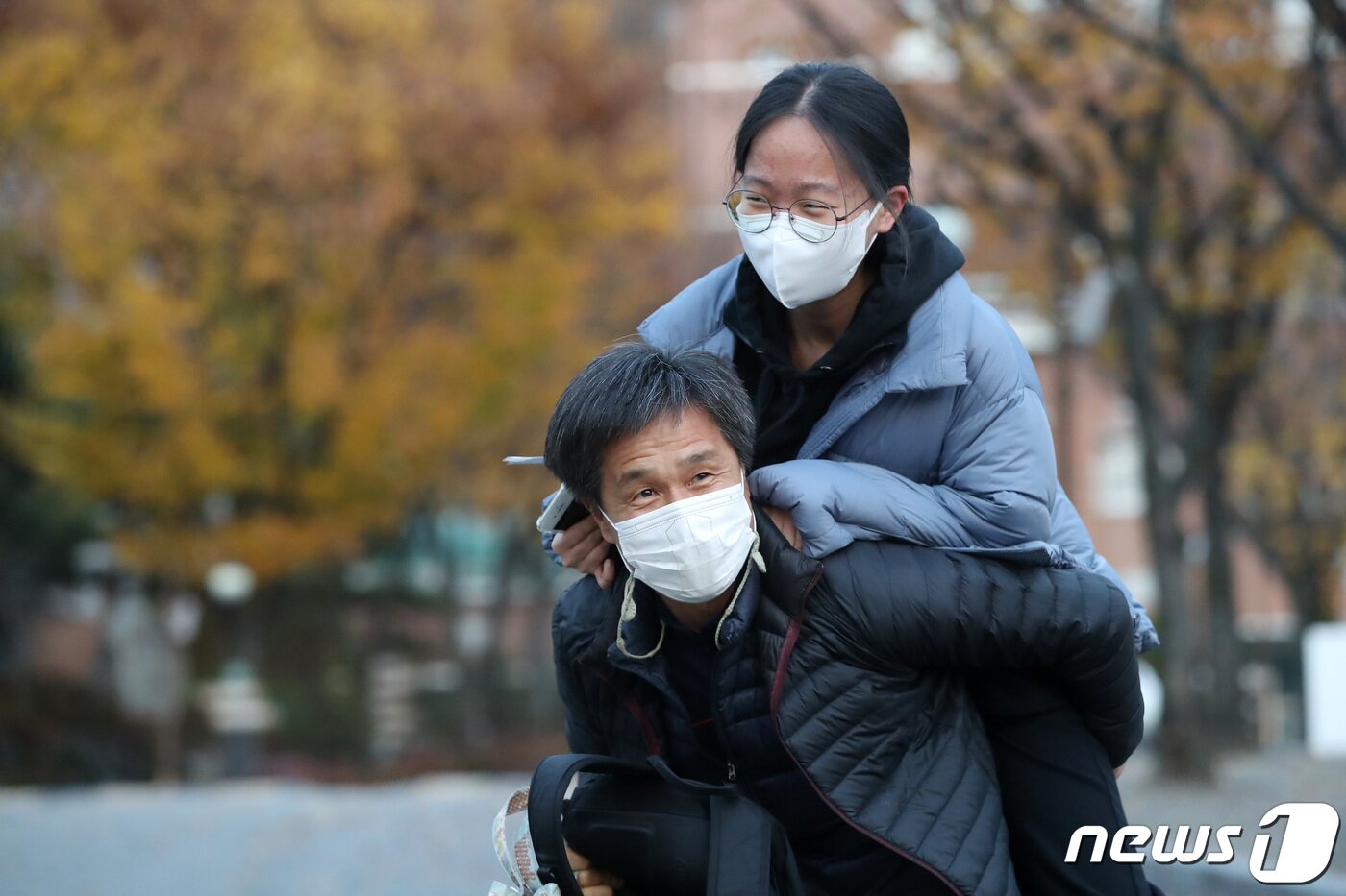 본문 이미지 - 18일 대구 한 고등학교 앞에서 수험생 아버지가 딸을 업어주고 있다. 2021.11.18/뉴스1 ⓒ News1 공정식 기자