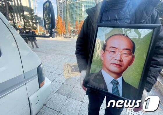 보수 성향 단체인 태극기혁명국민운동본부 회원이 24일 오전 서울 종로구 보신각 앞에서 전두환 전 대통령의 영정 사진을 차량으로 옮기고 있다. 이날 태극기혁명국민운동본부가 보신각 앞에 설치한 전 전 대통령의 추모 분향소는 철거됐다. 종로구청은 전 전 대통령의 분향소 설치를 준비 중이던 단체 측에 도로법 위반으로 금지를 통보했었다. 2021.11.24/뉴스1 © News1 이광호 기자