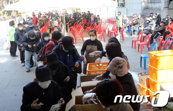 방역체계가 단계적 일상회복(위드코로나)으로 전환되고 있는 가운데 3일 오전 서울 종로구 탑골공원에서 원각사 무료급식소 봉사자들이 어르신들에게 도시락을 제공하고 있다. 2021.11.3/뉴스1 © News1 황기선 기자