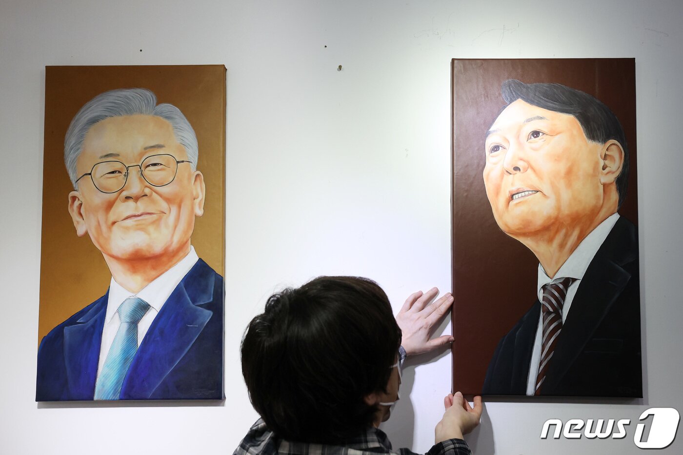 본문 이미지 - 5일 오후 서울시내 한 갤러리에서 관계자가 윤석열 국민의힘 대통령 후보의 초상화를 이재명 더불어민주당 대통령 후보의 초상화 옆에 전시하고 있다. 국민의힘 대선 경선 선거관리위원회는 이날 '국민의힘 대통령 후보자 선출 전당대회'에서 윤석열 경선 후보가 대선 후보로 확정됐다고 밝혔으며 윤 후보는 내년 3월9일 열리는 20대 대선에 출마해 이재명 더불어민주당 후보를 상대로 정권교체를 시도하게 됐다. 2021.11.5/뉴스1 ⓒ News1 조태형 기자
