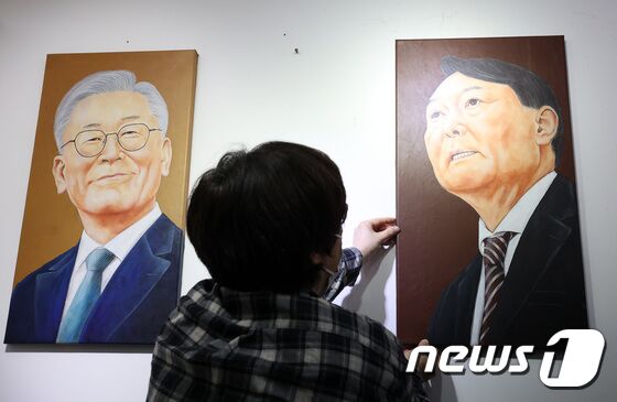 5일 오후 서울시내 한 갤러리에서 관계자가 윤석열 국민의힘 대통령 후보의 초상화를 이재명 더불어민주당 대통령 후보의 초상화 옆에 전시하고 있다. 2021.11.5/뉴스1 © News1 조태형 기자
