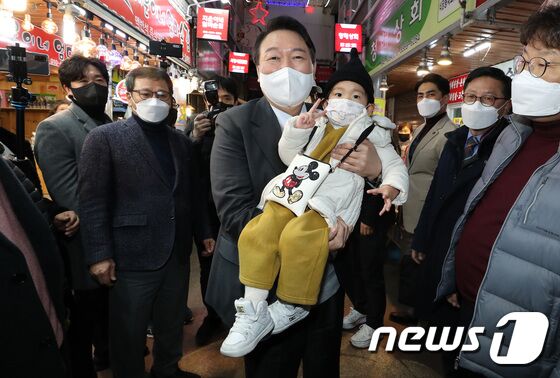 윤석열 국민의힘 대선 후보가 10일 저녁 강원도 강릉시 중앙시장을 방문해 한 어린이와 기념사진을 찍고 있다. 2021.12.10/뉴스1 © News1 이동해 기자