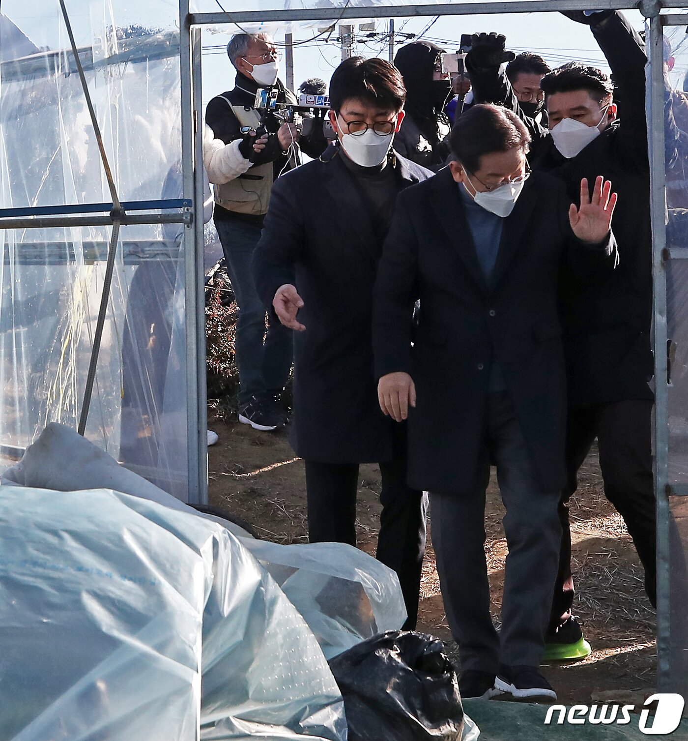 본문 이미지 - 이재명 더불어민주당 대선 후보가 13일 오전 대구·경북 매타버스 민생투어의 일환으로 경북 성주군의 한 참외 농가를 방문하다 사드 배치를 반대하는 지역 주민이 던진 계란이 날아들자 경호원에게 괜찮다며 손짓하고 있다. 사진 왼쪽 비닐하우스 외벽에 깨진 계란 자국이 보인다. 2021.12.13/뉴스1 ⓒ News1 오대일 기자