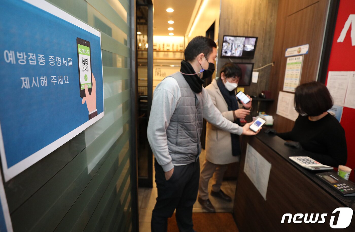 본문 이미지 - 방역패스&#40;접종증명·음성확인제&#41;의 계도기간이 끝나고 의무화가 시작된 13일 서울시내의 한 식당에서 손님들의 백신접종을 확인하고 있다. 이날부터 백신 미접종자, PCR검사 음성확인서 없이 식당·카페 등 16종의 다중이용시설을 이용하다가 적발되면 과태료를 물린다. 수기명부는 허용되지 않으며, 전자출입명부와 안심콜 사용이 원칙이다. 2021.12.13/뉴스1 ⓒ News1 박세연 기자