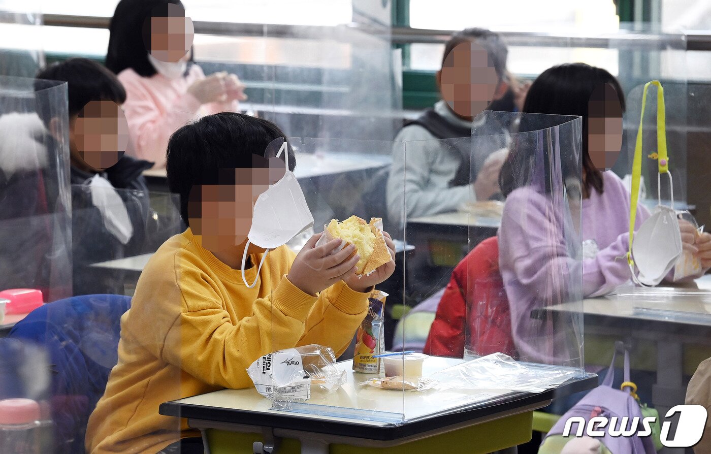 본문 이미지 - 급식 노동자, 돌봄 전담사, 방과 후 강사 등 학교 비정규직 노동자들로 구성된 전국학교비정규직연대회의가 총파업에 돌입한 2일 서울 시내 한 초등학교 학생들이 교실에서 빵과 쿠키 등으로 구성된 대체식을 배식받아 점심 식사를 하고 있다. 2021.12.2/뉴스1 ⓒ News1 박정호 기자