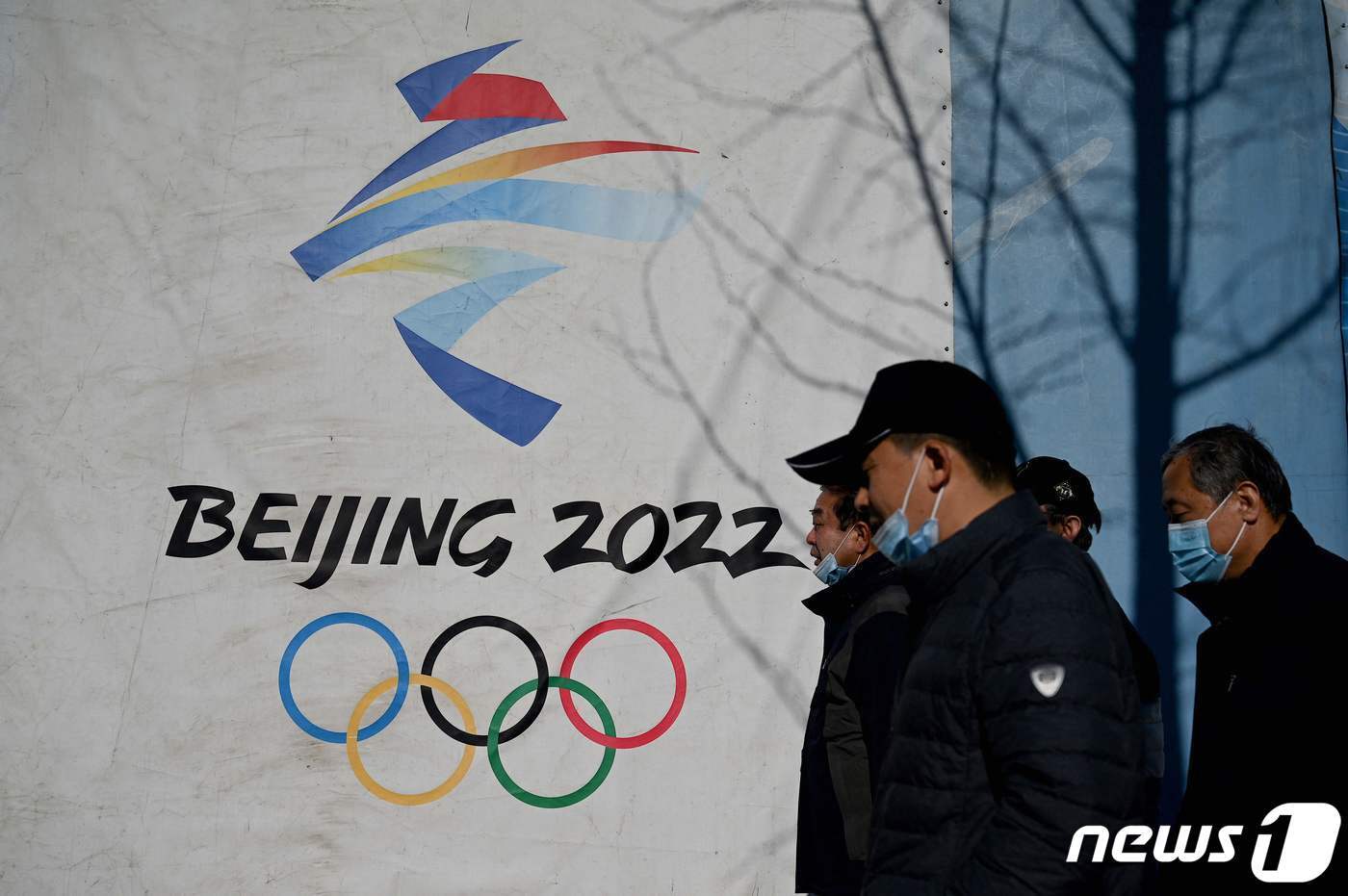 본문 이미지 - 2022 중국 베이징 동계올림픽 로고 앞을 지나는 베이징 시민들 <자료사진> ⓒ AFP=뉴스1