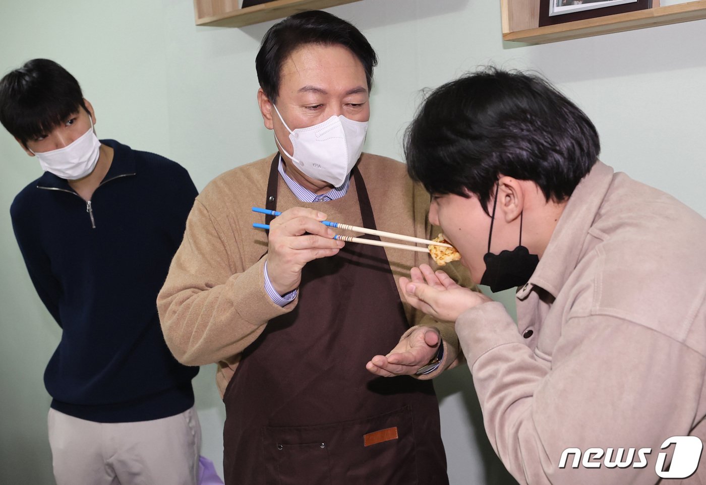 본문 이미지 - 2021년 12월 24일 당시 윤석열 국민의힘 대선 후보가 서울 구로구 고아권익연대를 찾아 이 시설 출신 학생에게 직접 요리한 반찬을 먹여주고 있다. 고아권익연대는 아동 고아와 18세가 넘어 시설을 퇴소한 이들의 권익을 보장하기 위해 만들어진 단체다. ⓒ News1 구윤성 기자