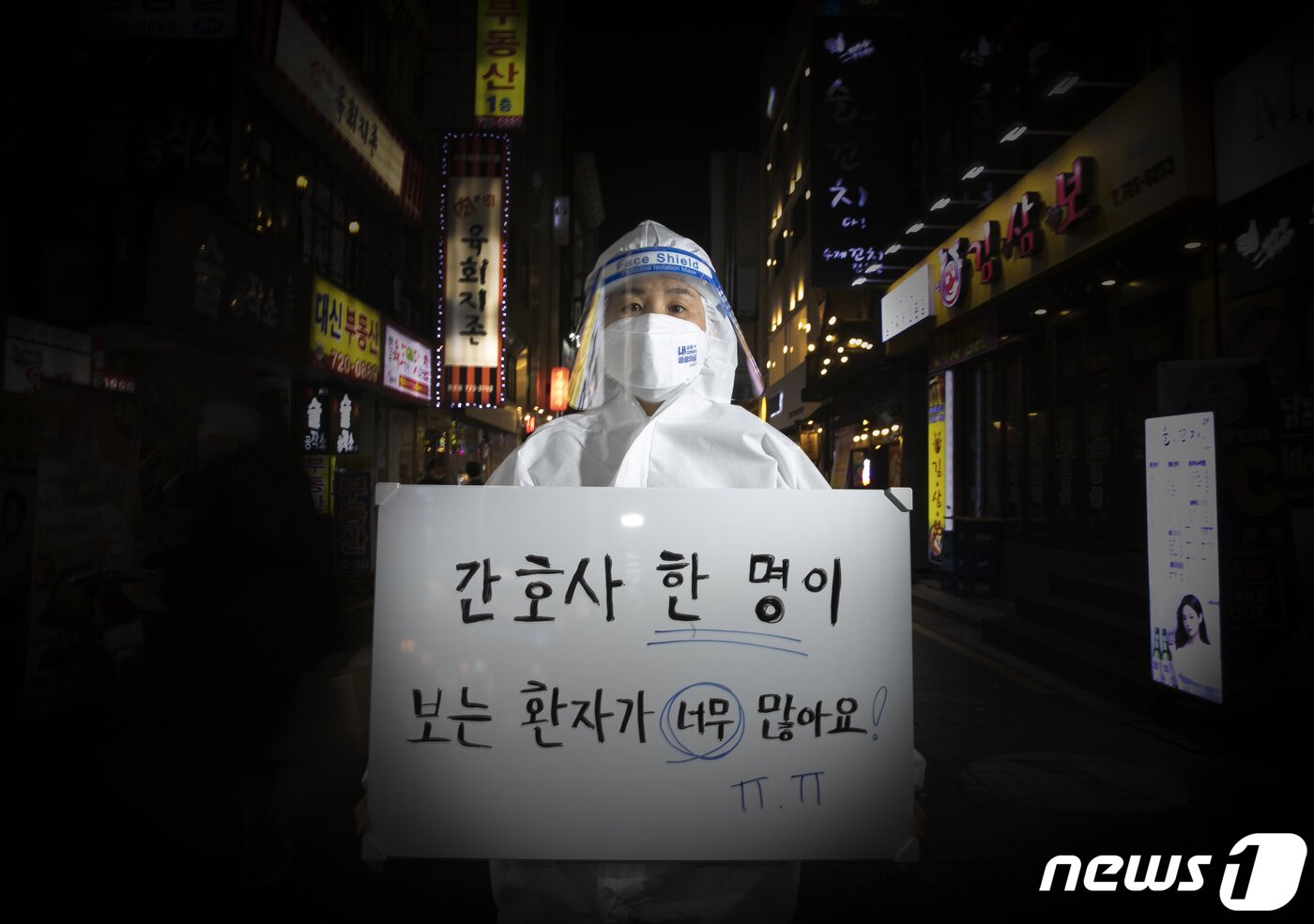 본문 이미지 - 지난 2021년 공공운소노조 의료연대본부 소속 김혜정 간호사가 네온사인이 빛나는 종로 유흥가에 새해 소원을 들고 선 모습. ⓒ 뉴스1 신웅수 기자
