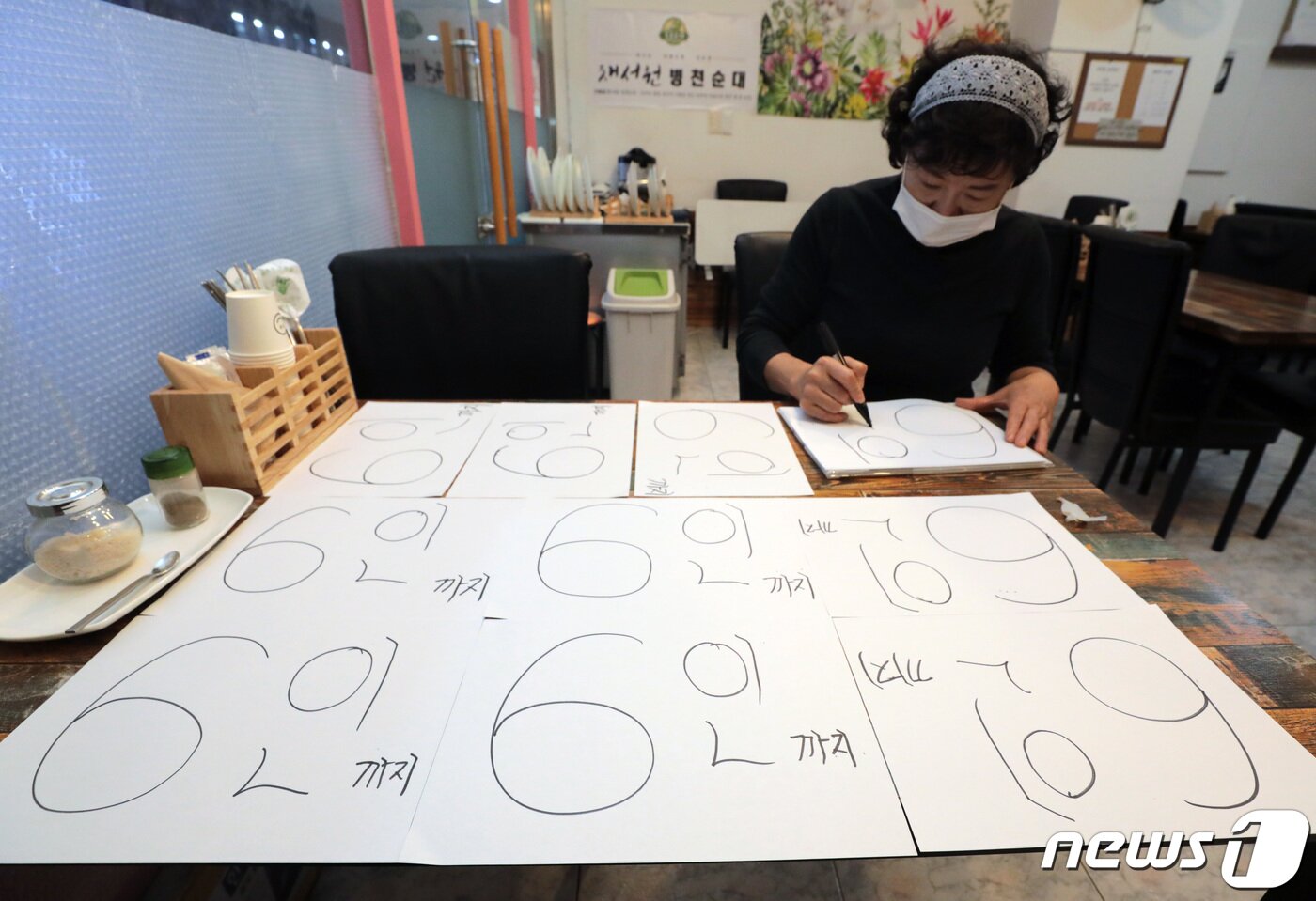 본문 이미지 - 정부가 수도권의 사적 모임 허용 인원을 기존 10인에서 6인으로 축소한 3일 서울 송파구의 한 음식점에서 관계자가 6인 안내문을 작성하고 있다. 사적모임 변동사항은 다음주부터 4주간 적용된다. 2021.12.3/뉴스1 ⓒ News1 이성철 기자