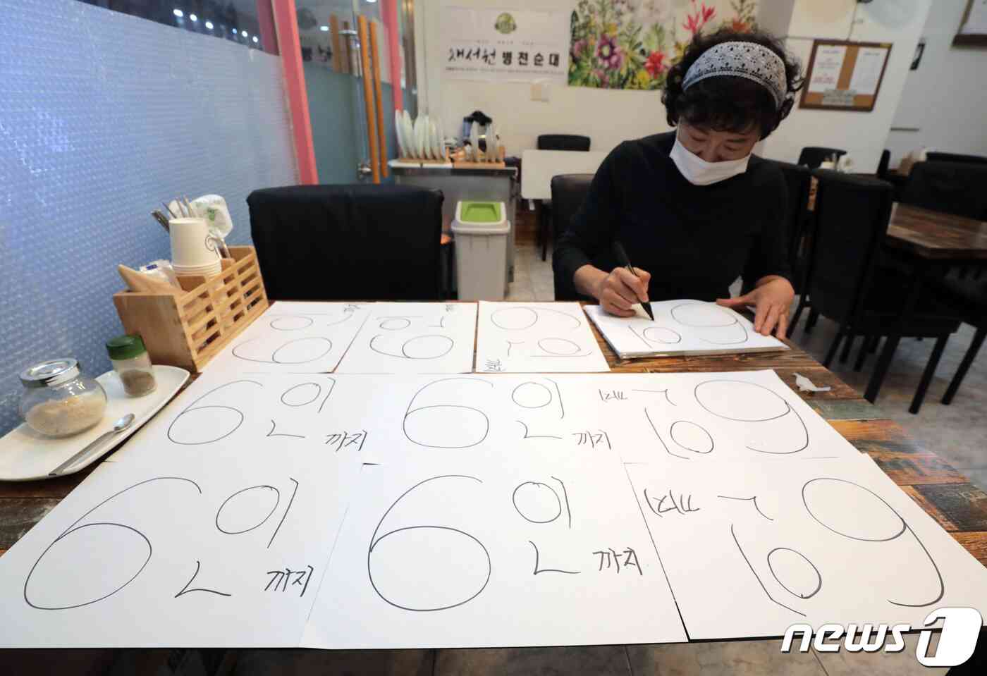 정부가 수도권의 사적 모임 허용 인원을 기존 10인에서 6인으로 축소한 3일 서울 송파구의 한 음식점에서 관계자가 6인 안내문을 작성하고 있다. 사적모임 변동사항은 다음주부터 4주간 적용된다. 2021.12.3/뉴스1 © News1 이성철 기자
