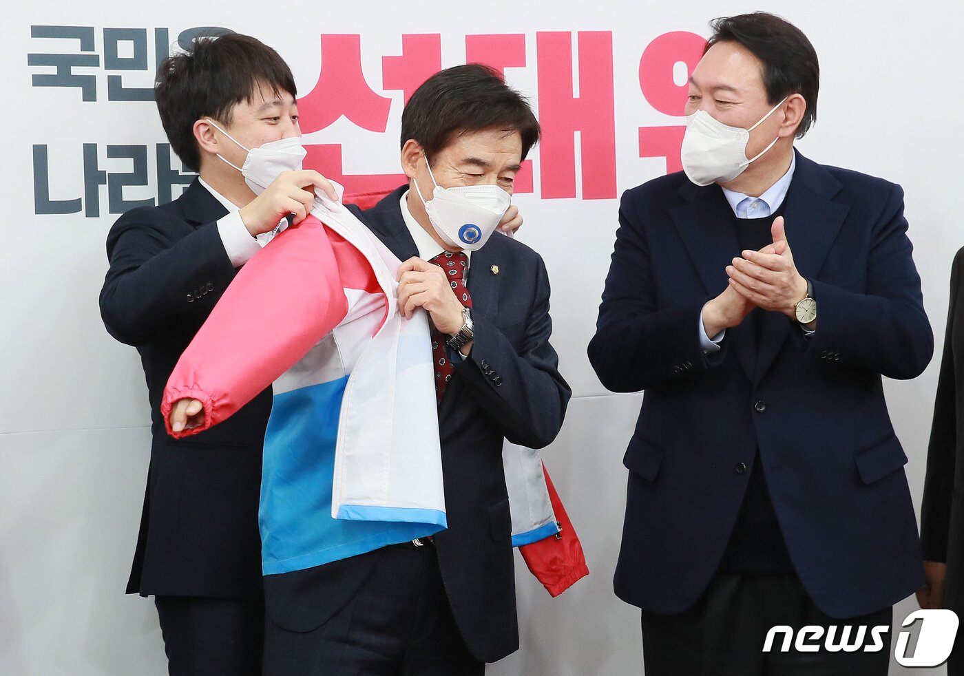 본문 이미지 - 이준석 국민의힘 대표(왼쪽)가 7일 오후 서울 여의도 국회에서 국민의힘에 입당한 이용호 의원(가운데)에게 당복을 입혀주고 있다. 오른쪽은 윤석열 대선후보. 이 의원은 2004년 새천년민주당 후보로 17대 국회의원 선거에 출마했지만 낙선했고, 2016년 20대 총선에서는 국민의당 후보로 전북 남원·순창·임실 지역구에서 당선됐다. 이후 국민의당과 바른정당의 합당에 반발하며 탈당했으며, 21대 총선에서는 호남에서 비(非) 민주당 후보로는 유일하게 재선에 성공한 바 있다. 2021.12.7/뉴스1 ⓒ News1 이동해 기자