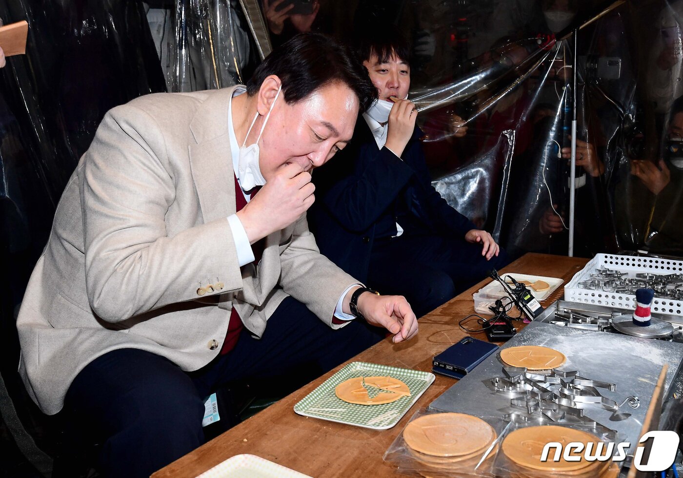 본문 이미지 - 윤석열 국민의힘 대선후보와 이준석 대표가 8일 서울 종로구 대학로에서 거리인사 중 한 달고나 가게에서 달고나 뽑기 체험을 하고 있다. 2021.12.8/뉴스1 ⓒ News1 국회사진취재단