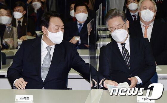 9일 오후 서울 마포구 연세대학교 신촌캠퍼스 김대중도서관에서 열린 김대중 대통령 노벨평화상 수상 21주년 기념식에서 윤석열 국민의힘 대선후보가 이재명 더불어민주당 대선후보에게 기념식과 관련한 안내책자를 전해주고 있다. 2021.12.9/뉴스1 © News1 국회사진취재단