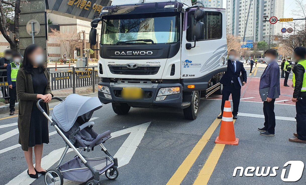 본문 이미지 - 18일 오전 광주 북구 운암동 어린이보호구역 사고 현장에서 현장검증이 진행되는 가운데 피해자 대역의 한 여성이 유모차를 끌고 화물차 앞에 서있다. 재판부는 "피해자가 보이지 않았다＂는 운전자 진술을 토대로 과실 입증을 위한 현장 검증을 실시했다. 지난해 11월 광주 스쿨존에서 발생한 사고로 4명의 일가족이 화물차에 치여 3세 여아가 숨졌다.광주지법 제공). 2021.3.18/뉴스1 ⓒ News1 허단비 기자