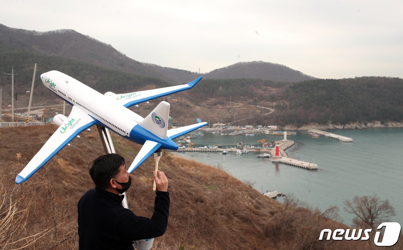 본문 이미지 - 4일 오전 부산 강서구 대항동 대항전망대에서 한 페인트 작업자가 비행기 모형에 적힌 신공항 건설 반대 문구를 지우는 페인트 작업을 하고 있다. 가덕도 신공항을 찬성하기 위해 설치한 이 비행기 조형물에는 'No Plane No Pain(비행기가 없으면 고통도 없다), '우리는 살고싶다'등 신공항 건설 반대 문구가 쓰여 있었다. 2021.3.4 /뉴스1 ⓒ News1 여주연 기자