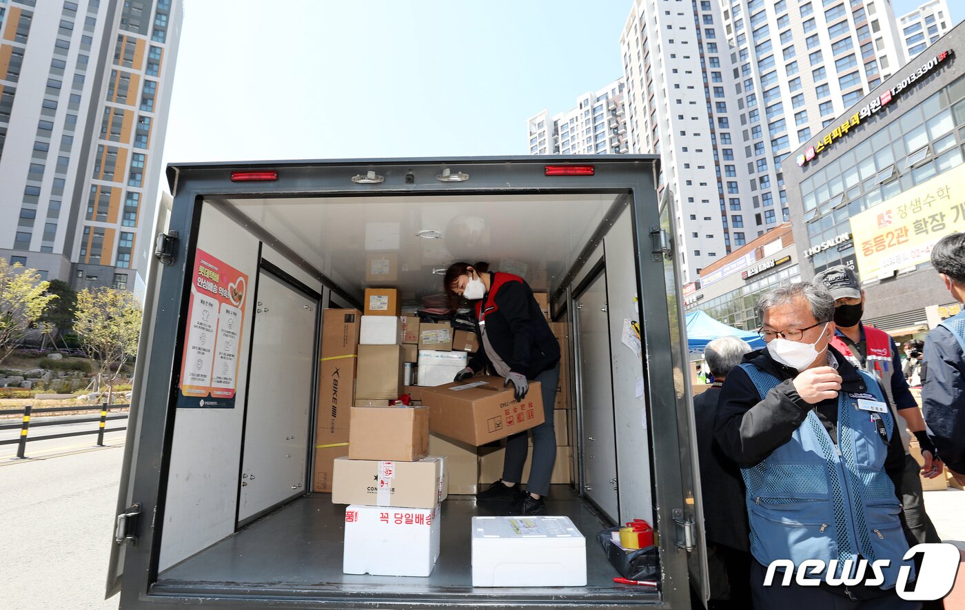본문 이미지 - 택배기사가 14일 단지 내 택배차량 진입이 제한된 서울 강동구 고덕동에 위치한 5000세대 규모 아파트 앞에서 허리를 제대로 펴기 힘든 높이의 저상 탑차에서 물건을 내리고 있다. 2021.4.14/뉴스1 ⓒ News1 박지혜 기자