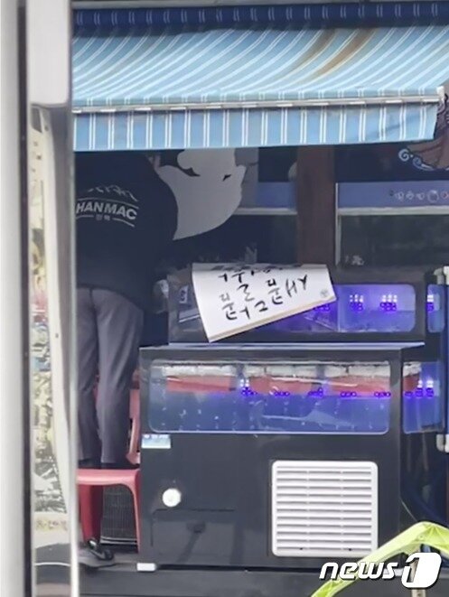 본문 이미지 - 30일 인천시 관교동의 한 식당에서 오비맥주 직원으로 추정되는 인물이 하이트진로의 홍보물을 제거한 뒤 '한맥'의 홍보물을 붙이고 있다. (하이트진로 제공) ⓒ 뉴스1