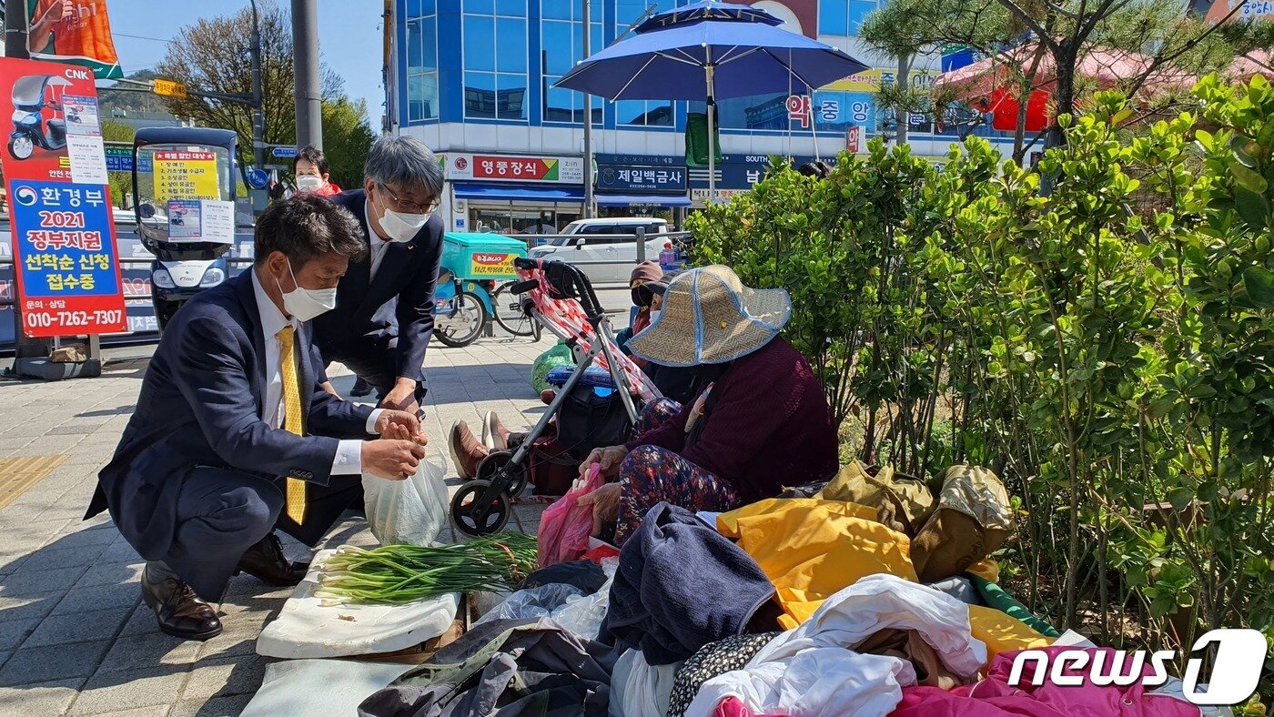 본문 이미지 - 여영국 정의당 대표가 9일 춘천 중앙시장 사거리 주변 장터에서 지역 주민들이 판매하는 나물류를 구매하고 있다. ⓒ 뉴스1 신관호 기자.