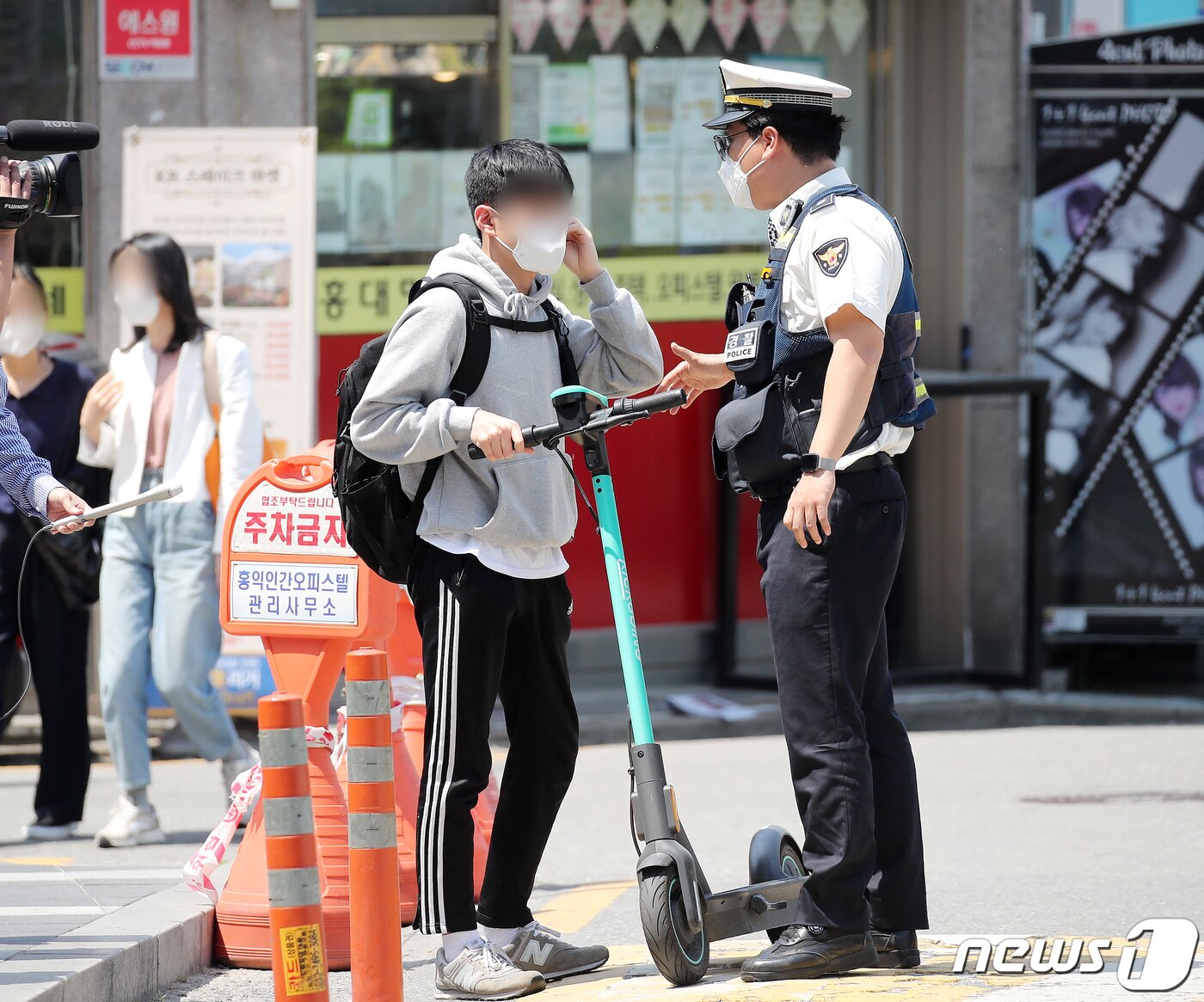 본문 이미지 - 전동킥보드 등 개인형 이동장치(PM)의 이용 규제를 강화하는 개정 도로교통법 시행이 시작된 13일 오후 서울 마포구 홍대입구역 인근 인도에서 마포경찰서 경찰들이 헬멧 없이 전동킥보드를 이용하는 시민에게 재개정 관련 내용 홍보 및 계도를 하고 있다. ⓒ News1 김진환 기자