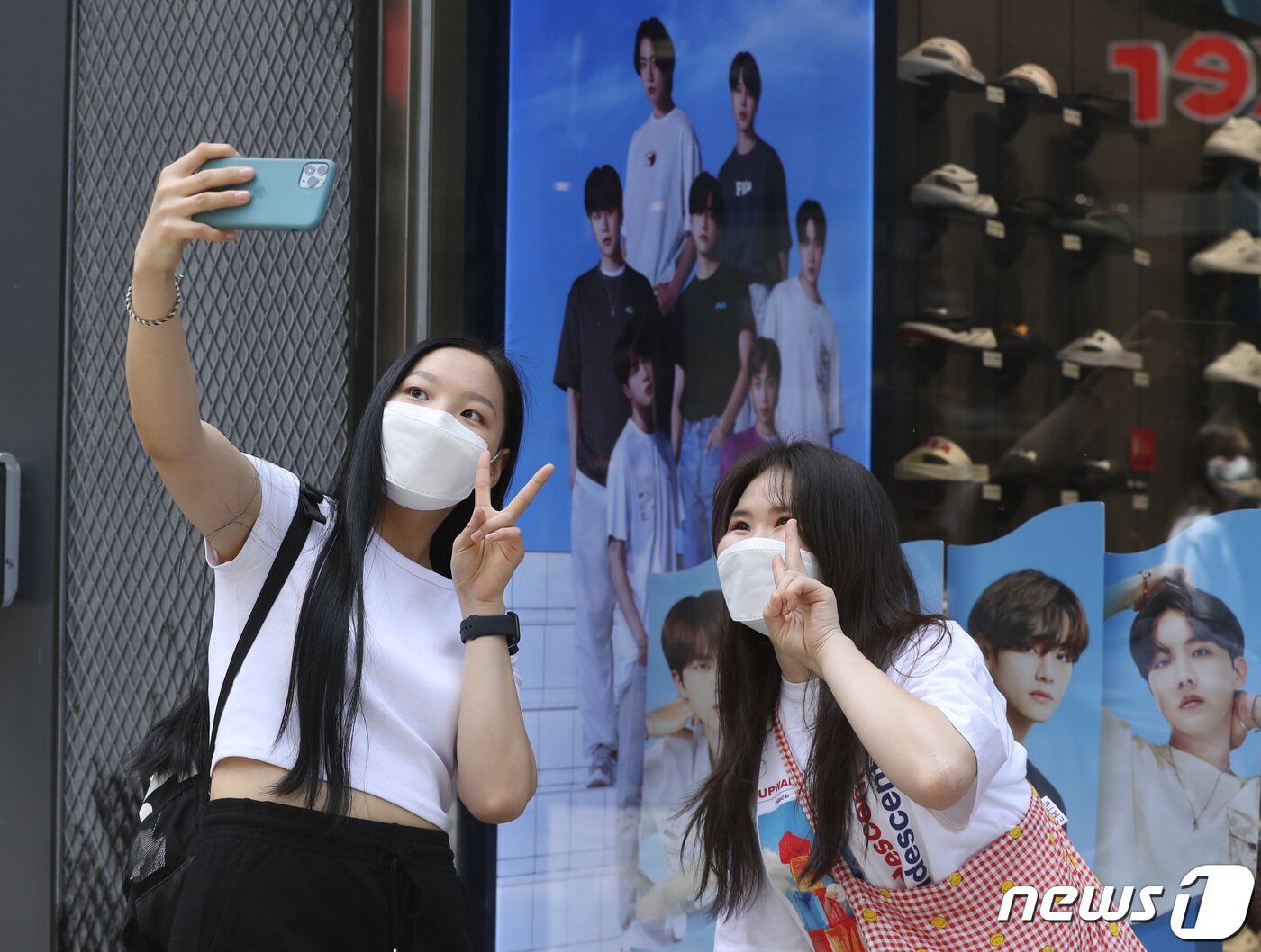 본문 이미지 - 서울 중구 명동 한 매장에 걸려있는 BTS의 광고 사진 앞에서 해외 팬들이 기념 촬영을 하고 있다.. 2021.5.24/뉴스1 ⓒ News1 권현진 기자