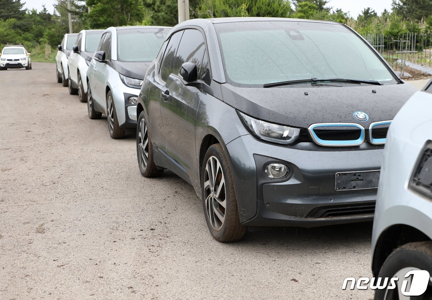 본문 이미지 - 26일 오전 제주 애월읍 중산간 목초지에 세워져 있던 BMW i3 100여 대가 서귀포에 있는 폐관한 공연장의 주차장으로 이동하고 있다. 이 차량들은 지난해 폐업한 렌터카업체의 소유였다.2021.5.26/뉴스1ⓒ News1 홍수영 기자