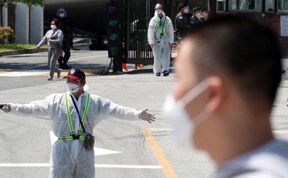 본문 이미지 - 전투복 위해 방호복까지 겹쳐 입은 육군훈련소 조교가 입영심사대에서 입영장병들에게 이동 장소를 안내하고 있다. ⓒ News1