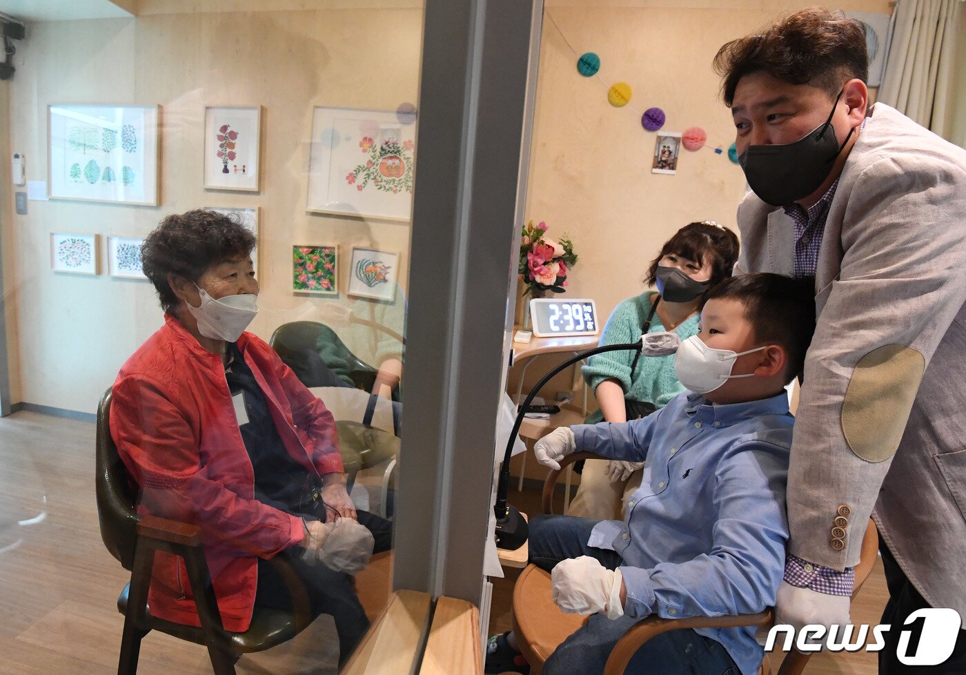 본문 이미지 - 어버이날을 앞둔 6일 서울 성동구 시립동부노인전문요양센터에 마련된 비대면 면회실 '가족의 거실'에서 박영순 할머니와 아들 강동훈 씨, 며느리 고의량 씨, 손자 강건우 군이 면회를 하고 있다. 2021.5.6/뉴스1 ⓒ News1 임세영 기자