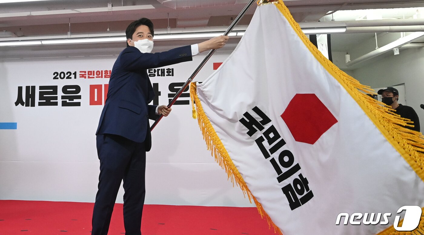 본문 이미지 - 이준석 국민의힘 신임 대표가 11일 오전 서울 영등포구 국민의힘 당사에서 열린 전당대회에서 당기를 흔들고 있다. '30대·0선'의 이 대표는 역대급 전당대회 흥행을 주도한 끝에 헌정사상 최초의 30대 보수정당 대표에 올랐다. 2021.6.11/뉴스1 ⓒ News1 오대일 기자