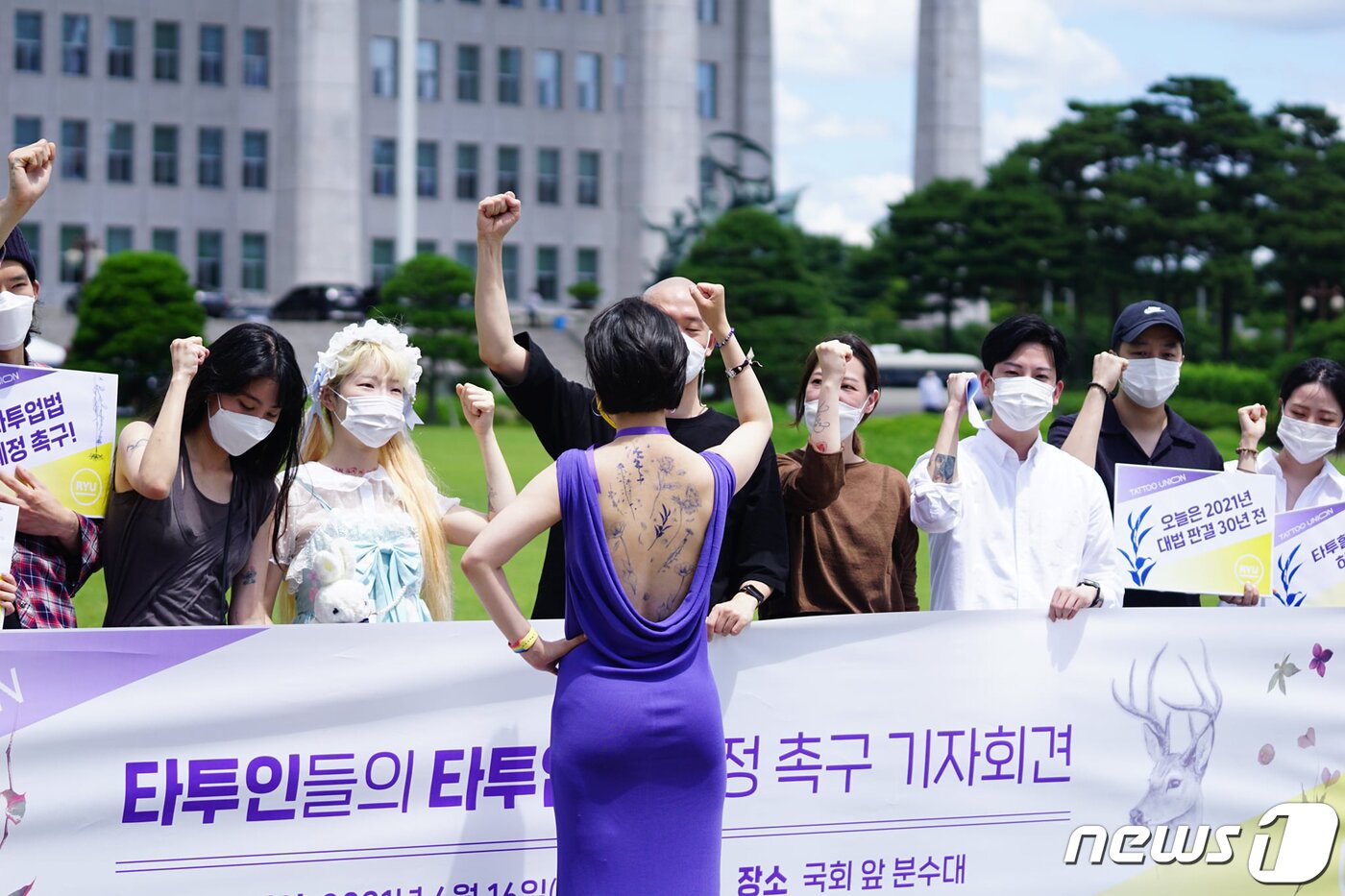 본문 이미지 - 류호정 정의당 의원이 16일 서울 여의도 국회 본관 앞에서 열린 '타투업법 제정 촉구 기자회견'에서 타투가 그려진 등이 노출된 보라색 드레스를 입은 채 구호를 외치고 있다. 류 의원은 ‘K-타투’ 산업 육성과 타투이스트 노동권 보호를 위해 지난 6월 11일 ‘타투업법’을 대표 발의했다. (류호정 의원 페이스북 캡처) 2021.6.16/뉴스1