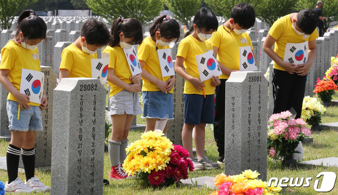 본문 이미지 - 현충일을 앞두고 2일 대전 유성구 국립대전현충원 1묘역에 위치한 묘비 앞에서 대전 남선초등학교 2학년 학생들이 직접 그린 태극기를 들고 추모하고 있다.  김기태 기자