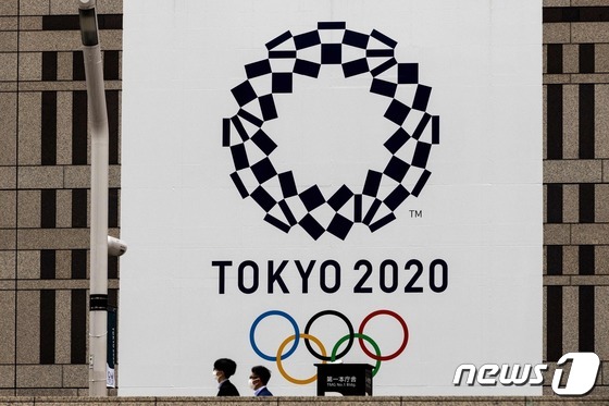 마스크를 착용한 시민들이 도쿄 올림픽 엠블럼 앞을 지나가고 있다.  © AFP=뉴스1