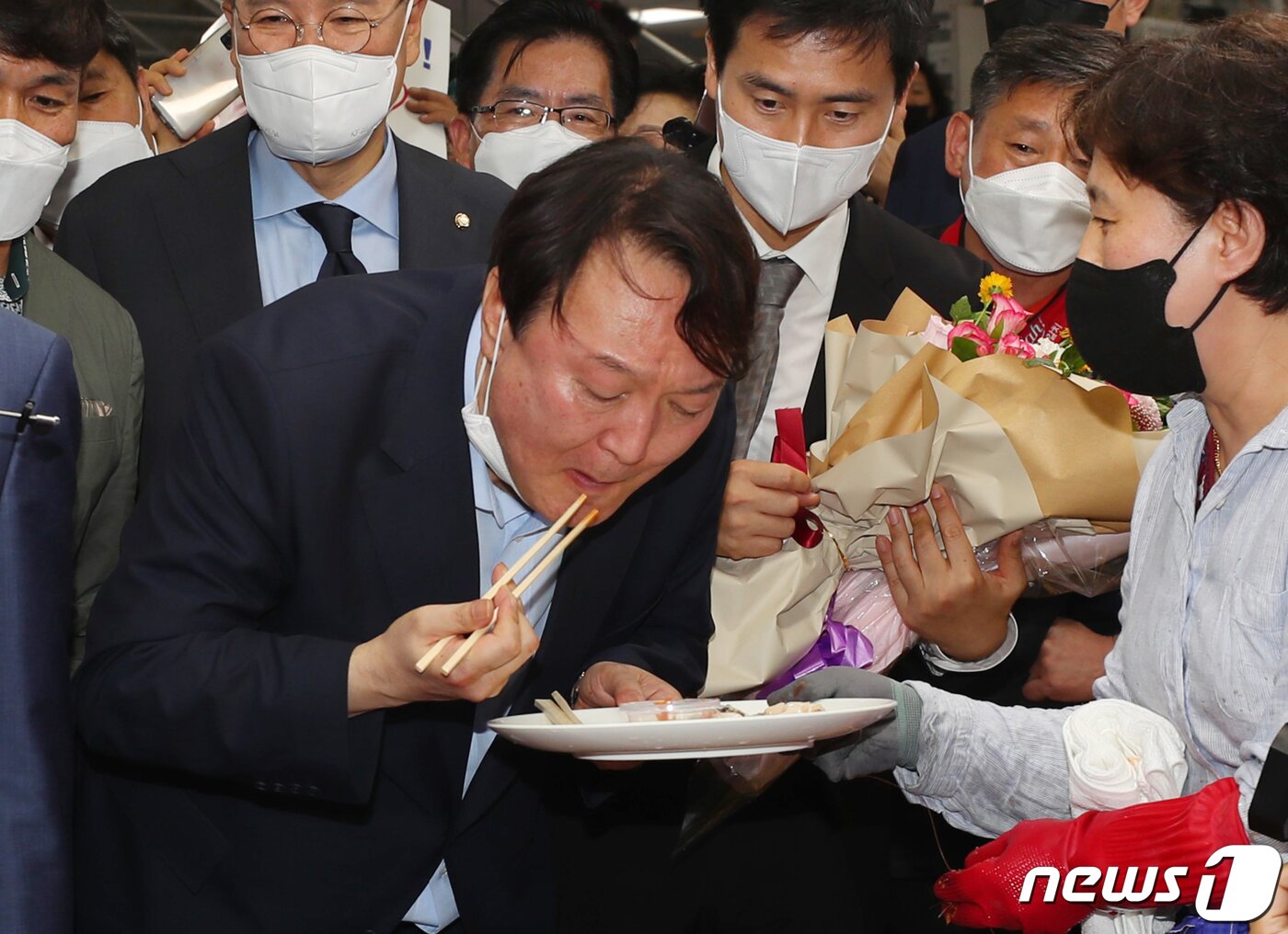 본문 이미지 - 윤석열 전 검찰총장이 27일 오후 부산 중구 자갈치시장을 찾아 상인이 건넨 전복을맛보고 있다. 2021.7.27/뉴스1 ⓒ News1 부산사진공동취재단