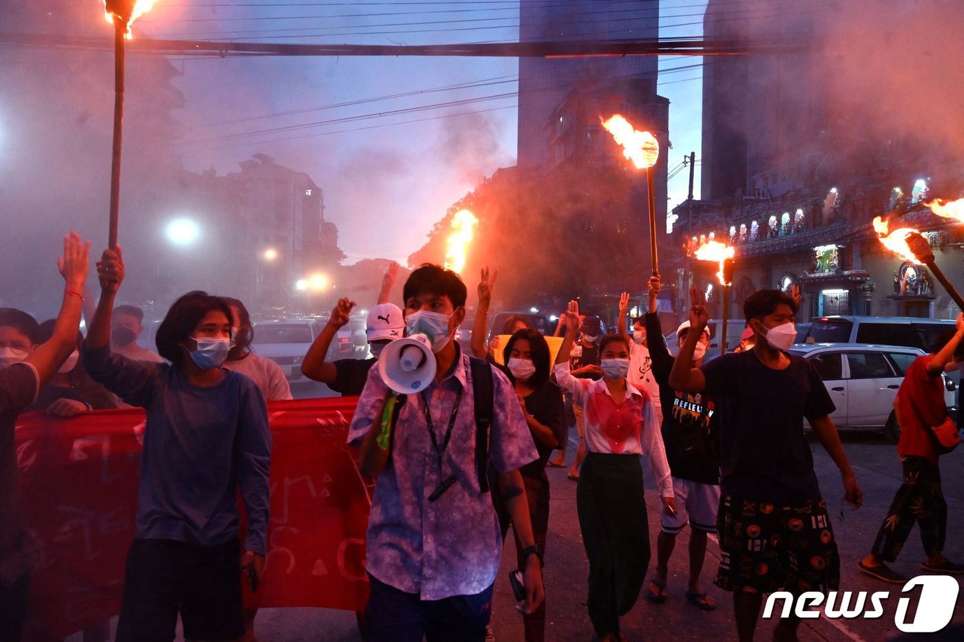 (양곤AFP=뉴스1) 서한샘 기자 = 29일(현지시간) 미얀마 양곤서 열린 군사 쿠데타 반대 시위에서 시위대가 횃불을 든 채 세 손가락 경례를 하고 있다.ⓒ AFP=뉴스1