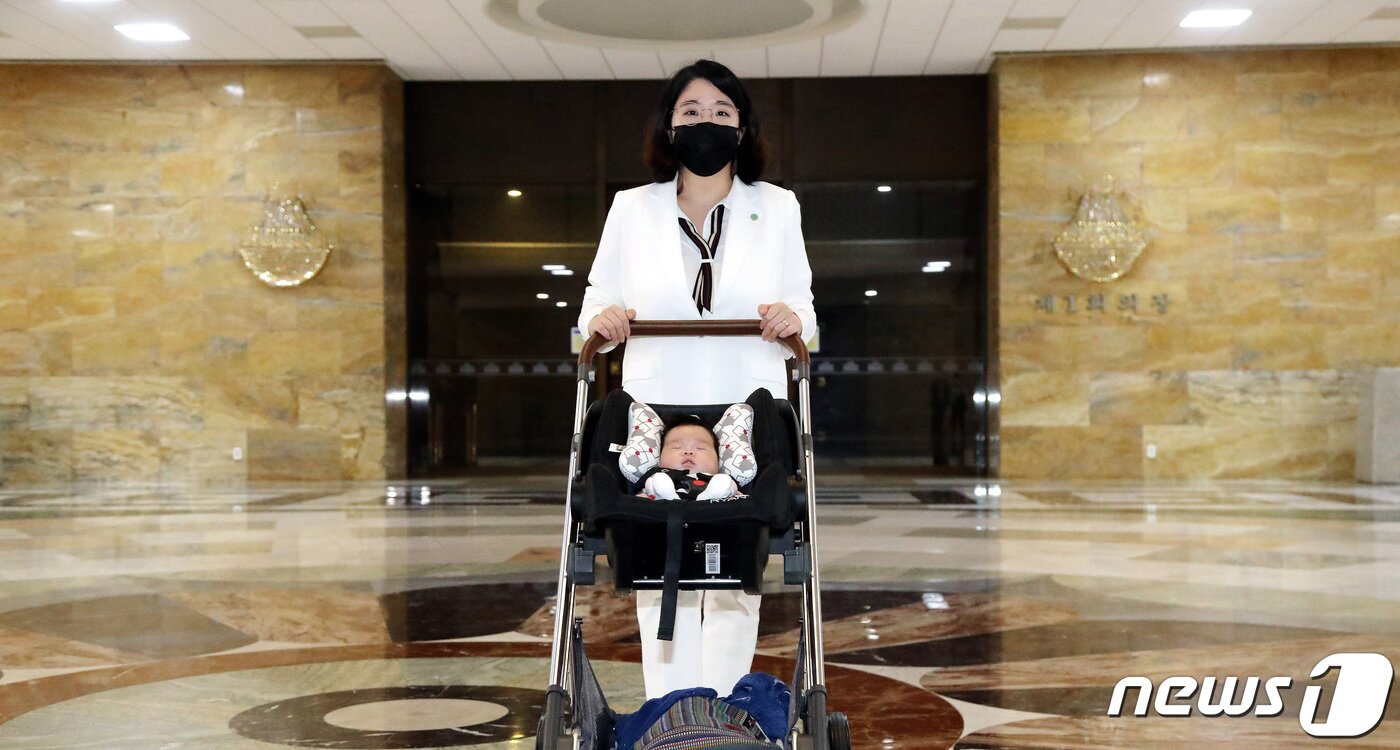 본문 이미지 - 출산휴가를 마치고 국회에 복귀한 용혜인 기본소득당 의원이 5일 아들과 함께 서울 여의도 국회 본회의장 앞을 지나고 있다. 용 의원은 지난 5월 17일 국회 회의장에 의원이 수유가 필요한 24개월 이하 영아와 함께 출입하도록 허용하는 내용의 '국회 회의장 아이동반법'을 발의했다. 구윤성 기자