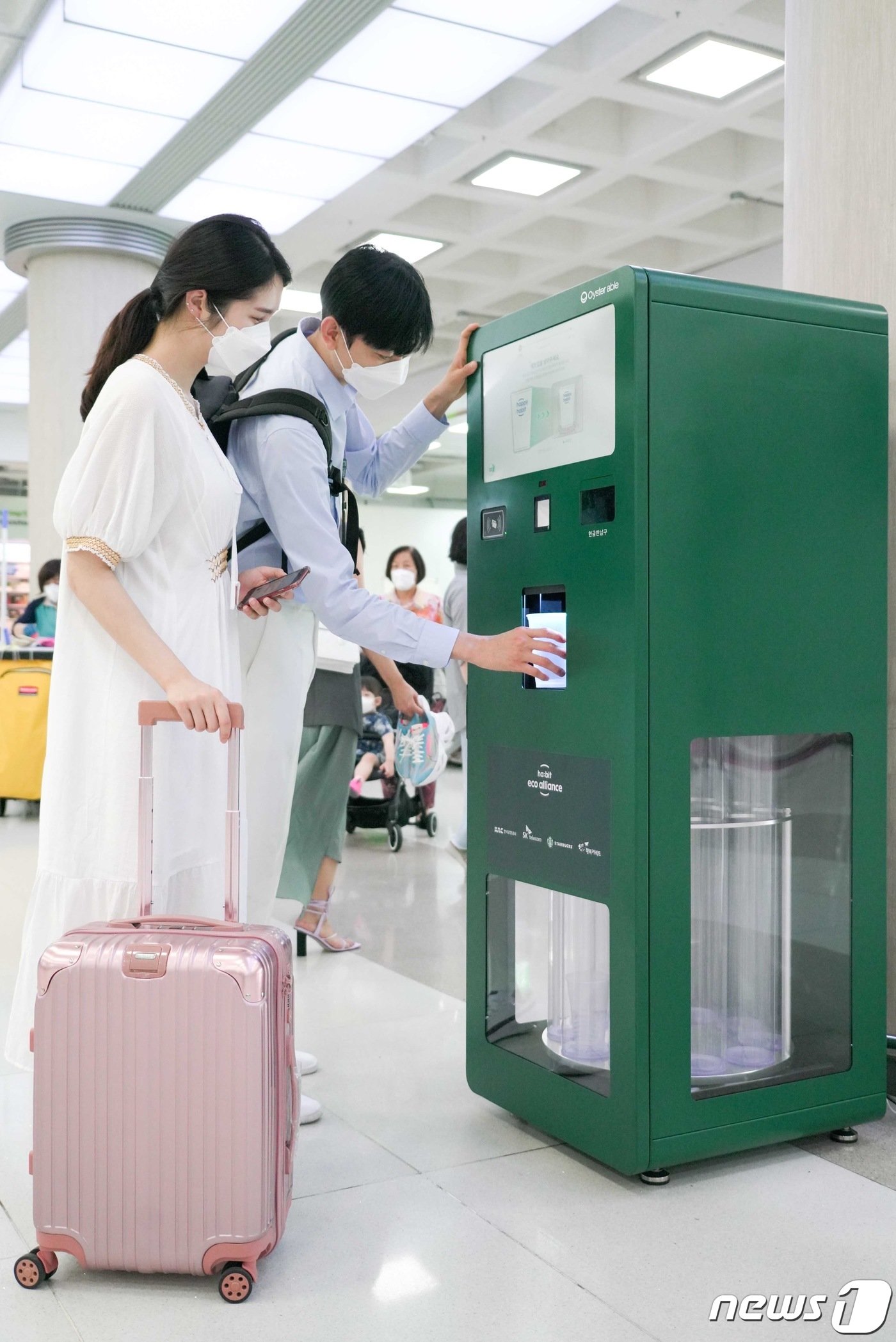 본문 이미지 - 제주 관광객들이 제주국제공항에 설치된 무인 반납기에 다 쓴 다회용 컵을 반납하고 있다.(SK텔레콤 제공) 2021.7.6/뉴스1