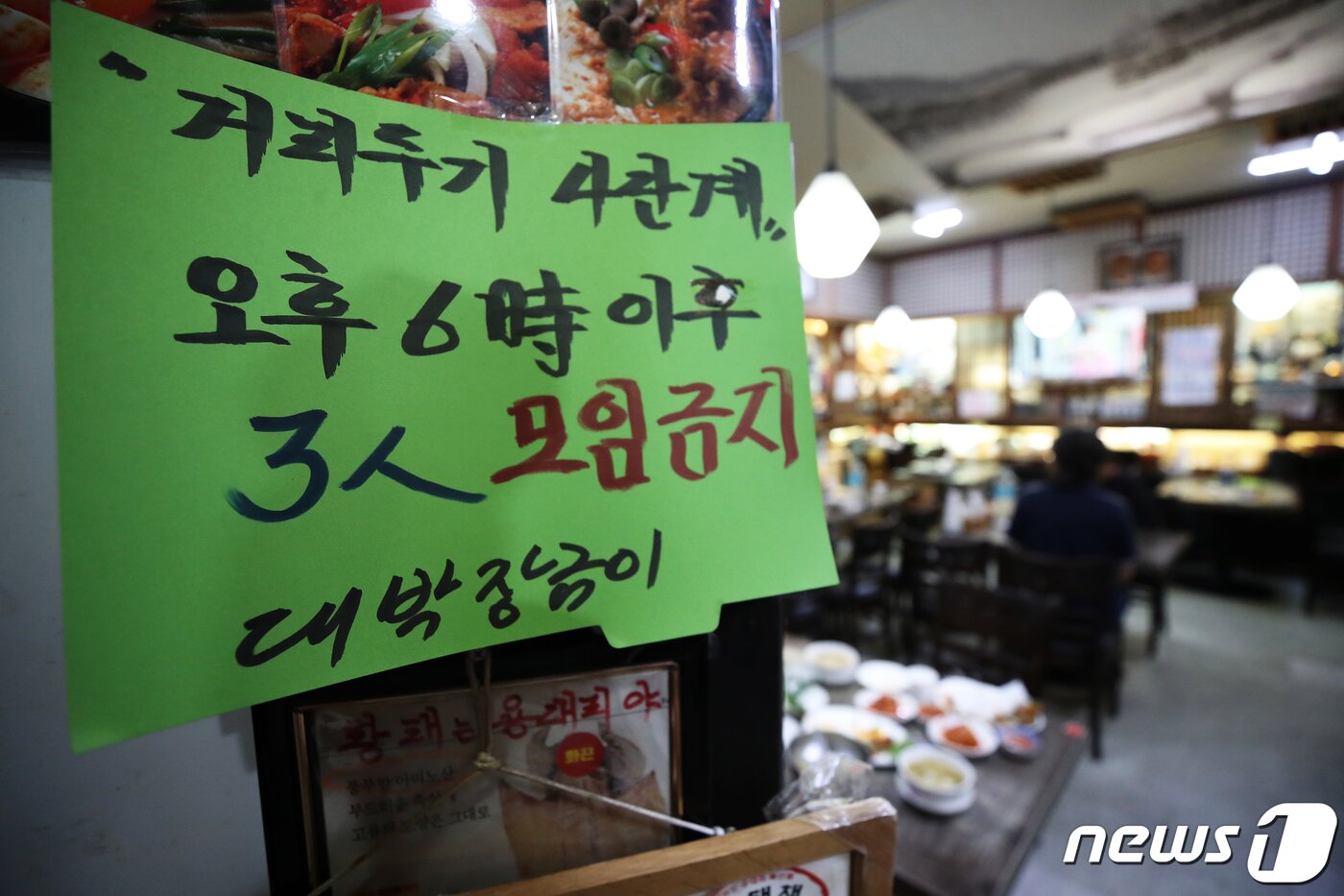 본문 이미지 - 신종코로나바이러스 감염증(코로나19) '4차 대유행'으로 수도권 사회적 거리두기 4단계 격상 소식이 발표된 9일 오후 서울 광화문의 한 음식점에 오후 6시 이후 3인 모임금지 안내문이 부착돼 있다. 오는 12일부터 2주간 적용되는 거리두기 4단계 조치가 시행되면 사적모임은 오후 6시 이후 2인 이하만 허용되며, 백신접종자에 대한 방역 완화 역시 유보된다. 이는 현행 거리두기 체계에서 가장 강력한 봉쇄조치로 사실상 ‘셧다운’에 해당한다. 2021.7.9/뉴스1 ⓒ News1 오대일 기자