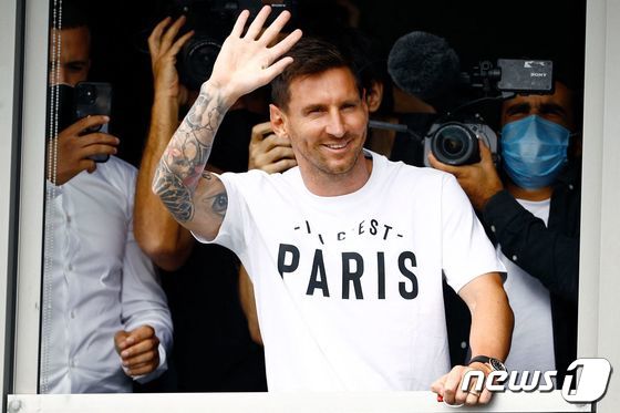 프랑스 프로축구 파리 생제르맹(PSG)과 계약을 앞둔 리오넬 메시가 지난 10일(현지시간) 파리 인근 르부르제 공항 창가에서 '여기는 파리입니다' 라는 PSG 슬로건이 적힌 흰색 티셔츠를 입고 팬들을 향해 손을 흔들고 있다. © AFP=뉴스1