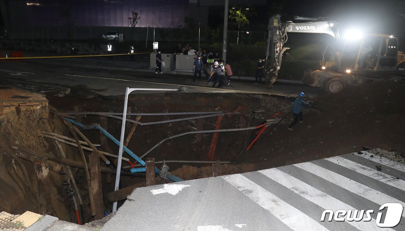 본문 이미지 - 11일 오후 10시50분쯤 대구 동구 괴전동 한국농수산식품유통공사 안심비축기지 앞 도로(반야월 연꽃단지·안심차량기지사업소 입구) 주변에서 교통사고를 처리하던 경찰관이 길이 10ｍ, 깊이 5ｍ 규모의 싱크홀(땅 꺼짐)을 발견했다. 12일 오전 2시쯤 경찰과 관계기관이 싱크홀 현장 주변을 통제한 뒤 중장비를 동원해 응급복구를 진행하고 있다. 2021.8.12/뉴스1 ⓒ News1 공정식 기자