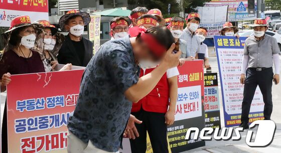 17일 정부세종청사 국토교통부 앞에서 한국공인중개사협회 회원들이 정부의 중개수수료 인하 추진 중단 촉구 집회를 갖던 중 한 참가자가 국토부에 항의하며 머리에 유리병을 부딪히고 있다. © News1 장수영 기자