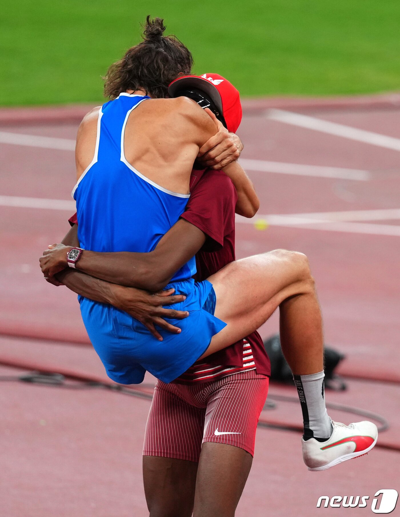 본문 이미지 - 2020년 도쿄 올림픽 남자 높이뛰기에서 금메달을 공유한 무타즈 바르심(카타르)과 지안마르코 탐베리(이탈리아). 탐베리가 훌쩍 뛰어 바름심에 안기고 있다. ⓒ 로이터=뉴스1 ⓒ News1 박형기 기자